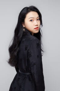 Long Black hair Asian female in a black suit.