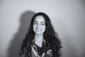 A grayscale Picture of Apoorva who has long wavy black hair and is wearing a scarf around her neck