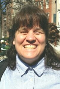 Closeup of Dr. Cheryl Fogle-Hatch smiling with her eyes closed. Cheryl is a white woman with shoulder-length brown hair.