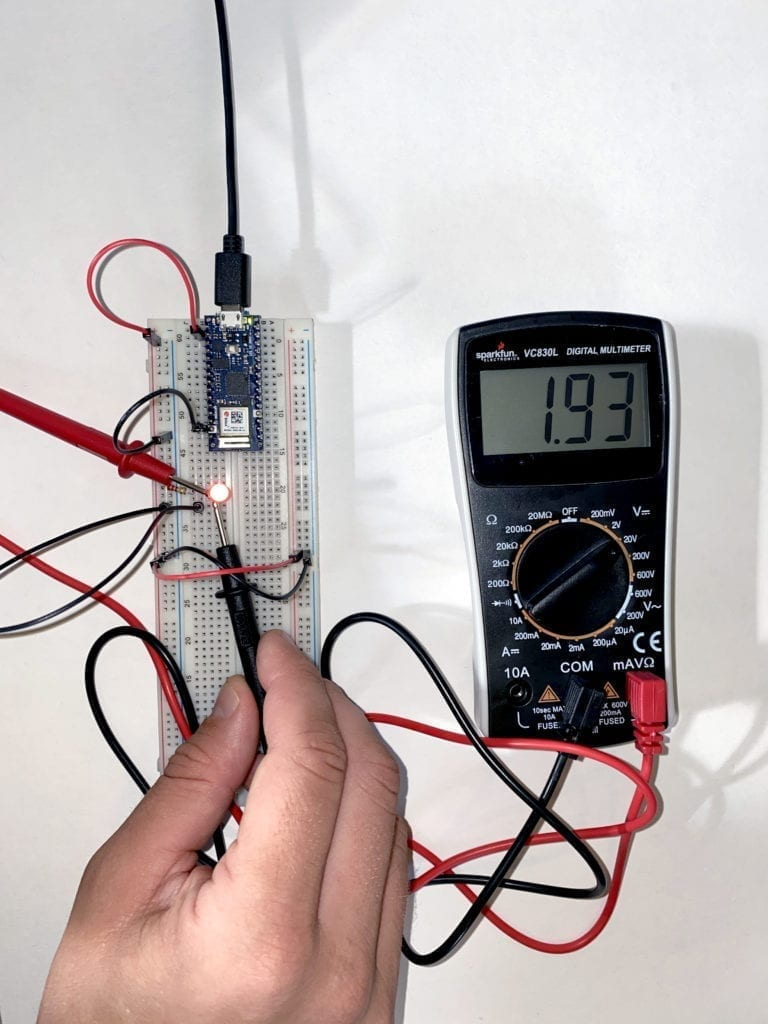 An image of a multimeter measuring the current running to and LED on a breadboard.