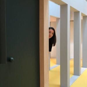 Caitlin peering out from behind a door