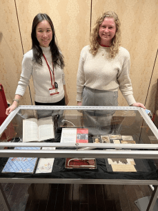 Alyssa Moore standing next to a display case at the annual SMARTFest containing curated items from the archives' collections.