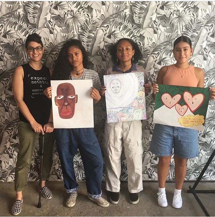 Four students posing with their artwork.