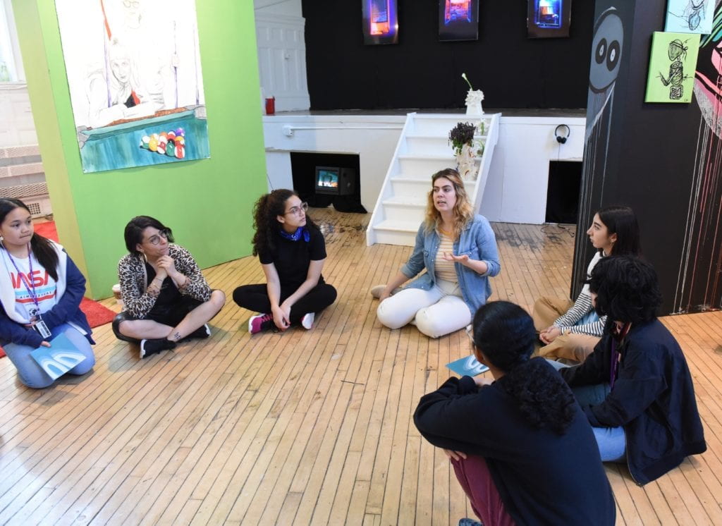 Students sitting in a circle on the floor of the gallery