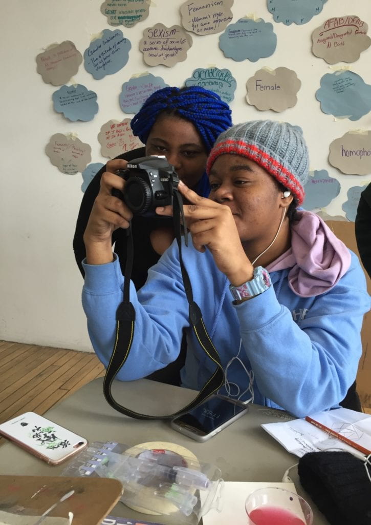 A student and teacher looking at a photograph on a camera. 