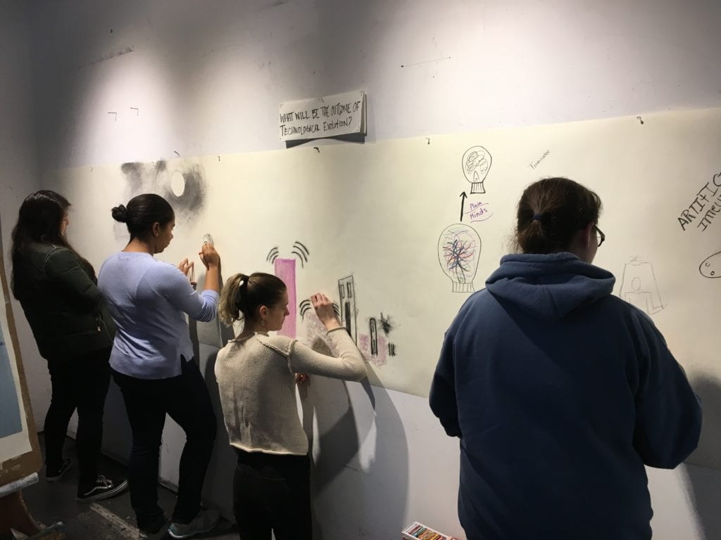 Students drawing on large piece of paper together