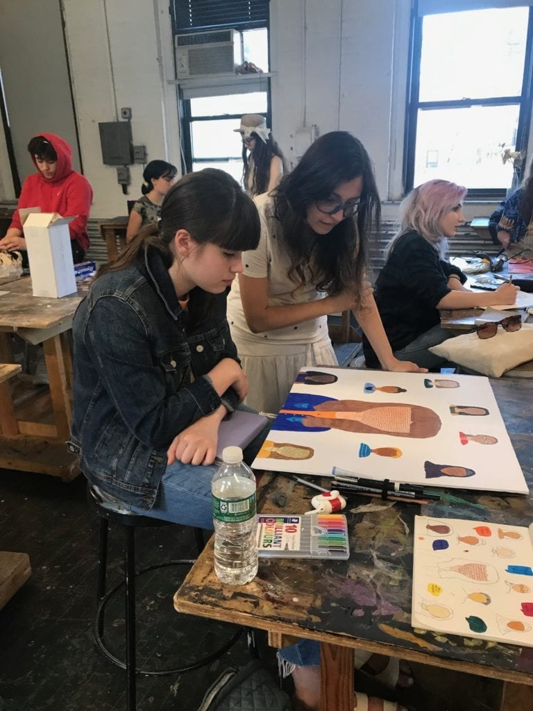 A student and teacher looking at the student's artwork together. 