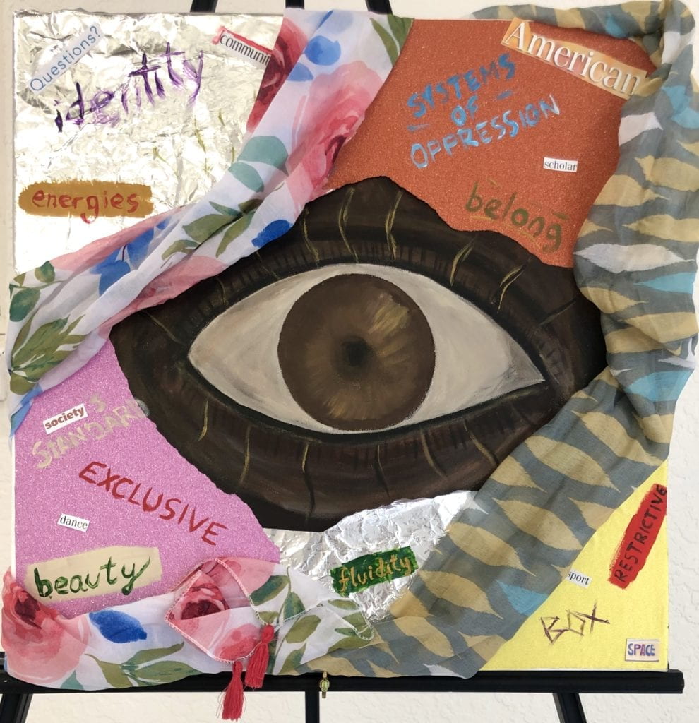 Image of student work of collage of an eye surrounded by words using fabrics and paint