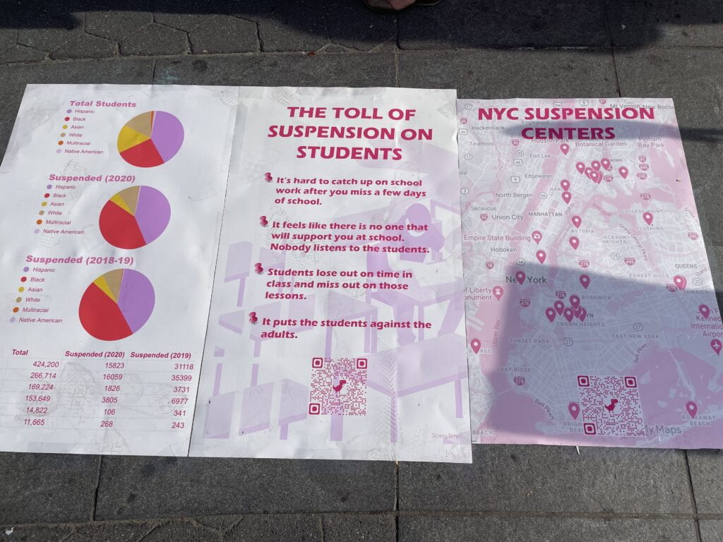 Image of posters that are on the ground. They include statistics and pie charts describing suspension rates in New York City