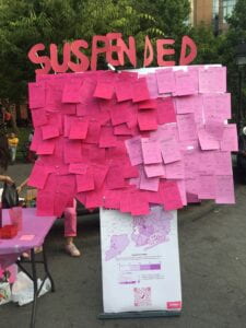 Image of a bulletin board with many pink slips attached to it. The top of the board says "Suspended"