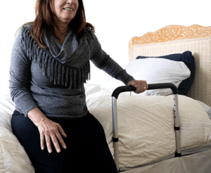 A person grabbing the handle of a device while sitting on a bed.