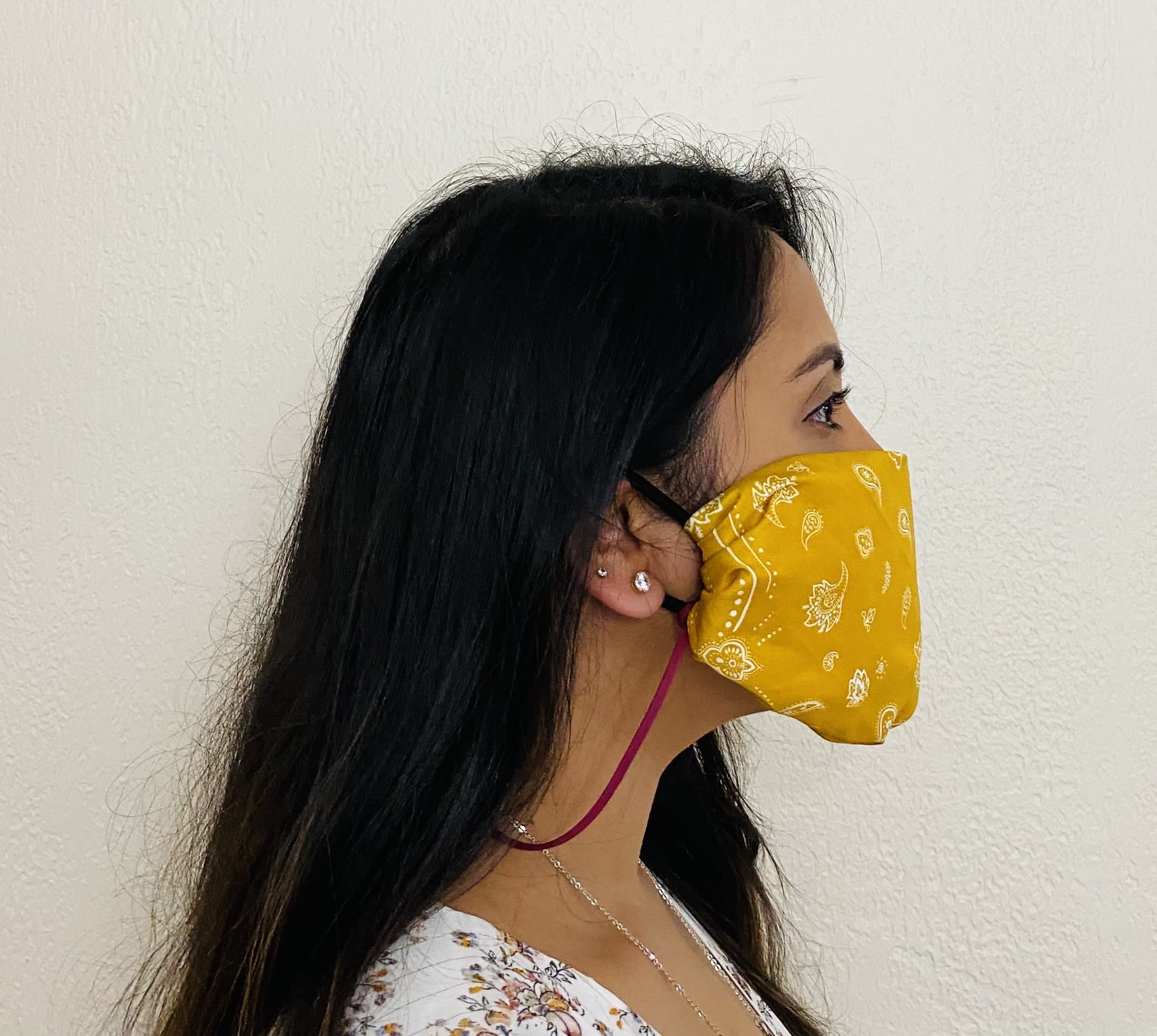 A yellow Bandana Mask is donned to cover nose and mouth. This image shows a Side-view of the bandana mask that is donned.