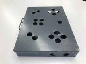 Metal box with seventeen holes on the top in the shape of a game controller configuration