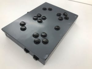 Metal box with black buttons in the shape of a game controller