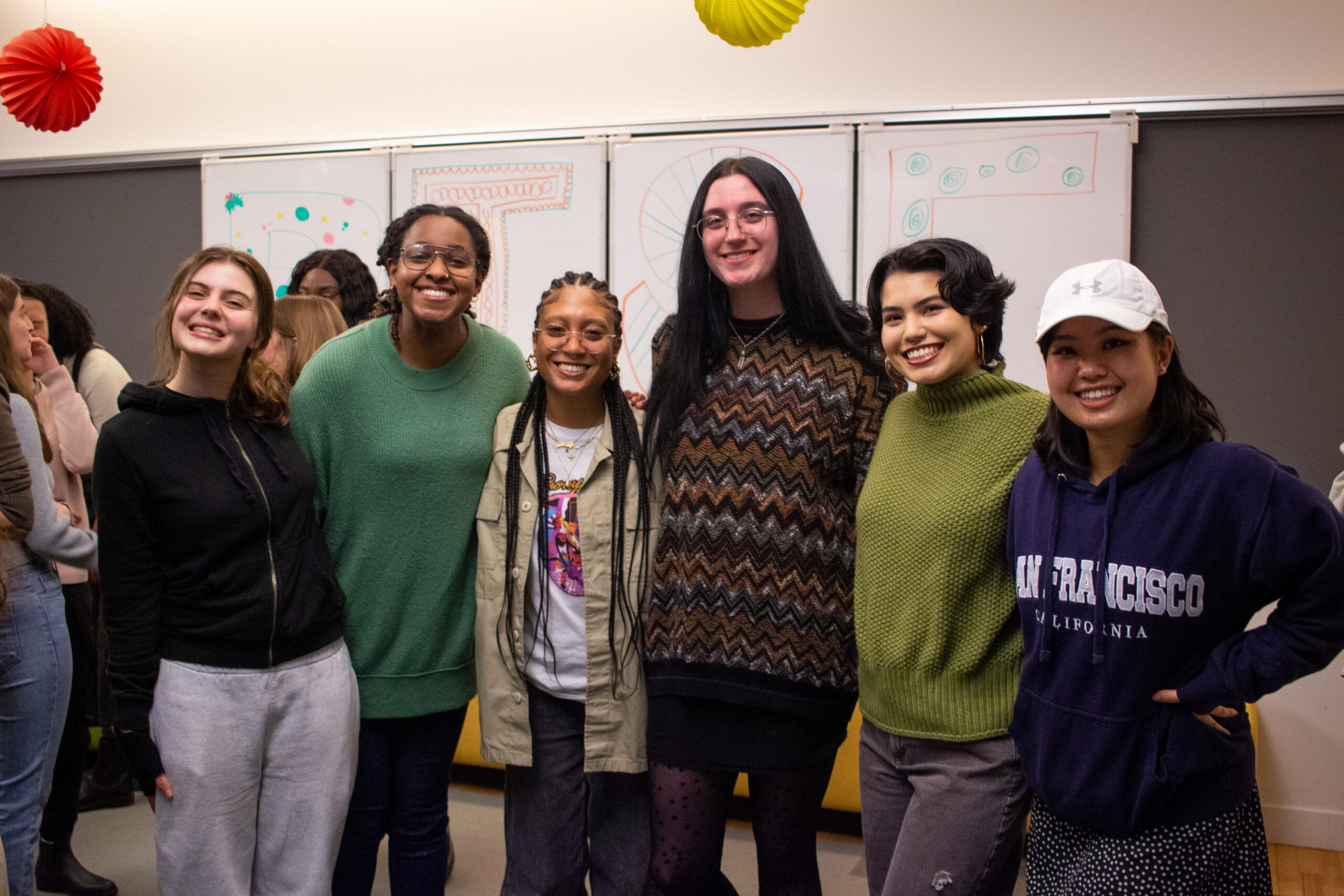 6 young people standing and smiling at the camera.