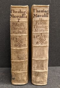 Book spines with handwritten text at top and decoration.