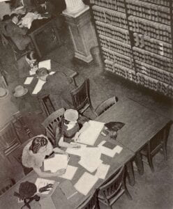 A view from above of students at long tables in the library.