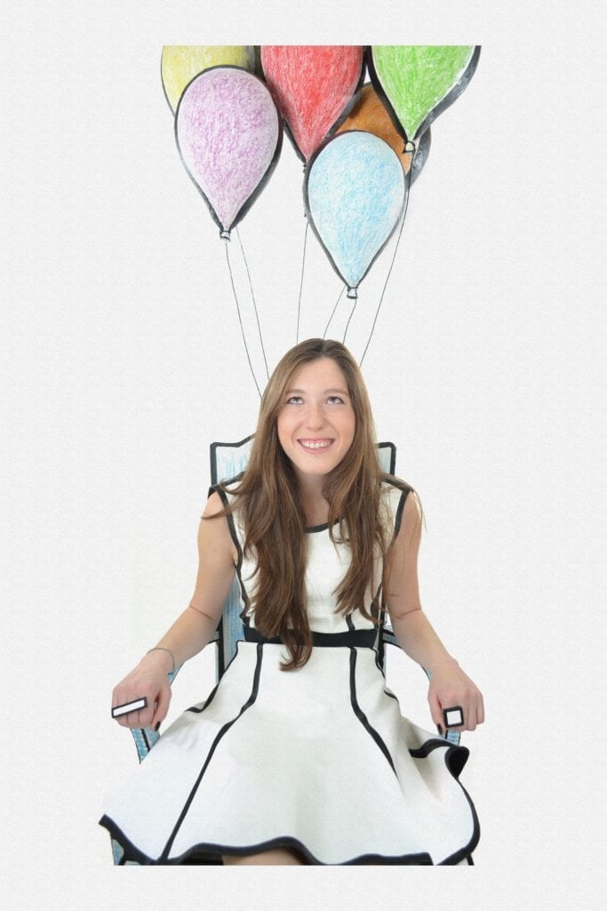 woman sitting in a chair tied with balloons 