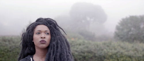 Woman looking out wuth a foggy woods behind her.