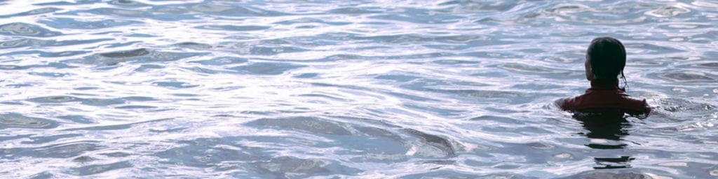 Woman in the ocean up to her shoulders.