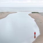 Far away shot of a woman standing ankle deep in water