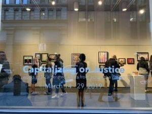 White text on a window reading "Capitalizing on Justice"