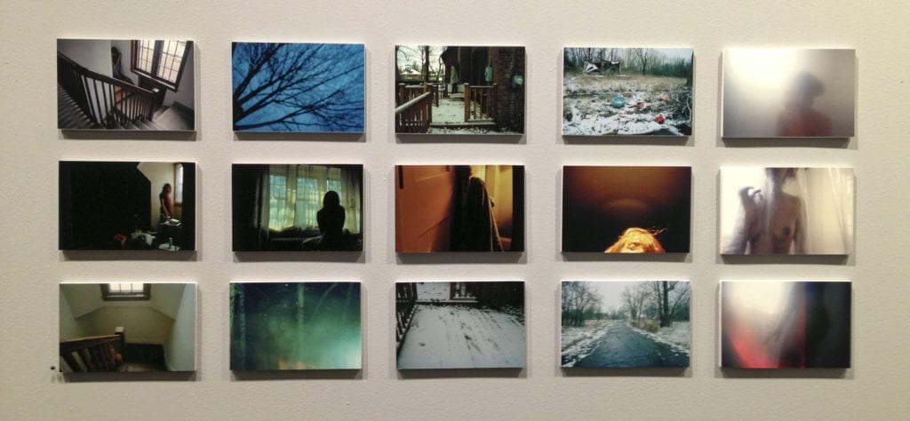 Fifteen photography prints of various subjects hang on a wall.