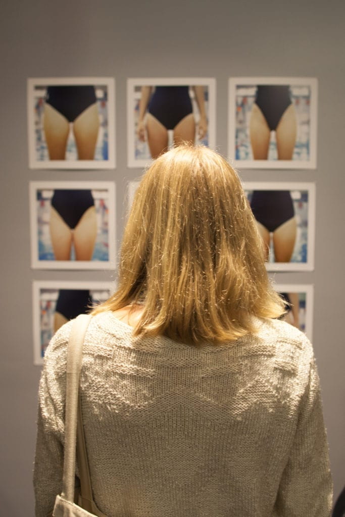 Blonde person viewing multiple photography prints of a woman wearing a black unitard.