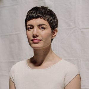 Headshot of Avery Trufelman. She has brown hair in a pixie cut and is wearing a white tshirt.