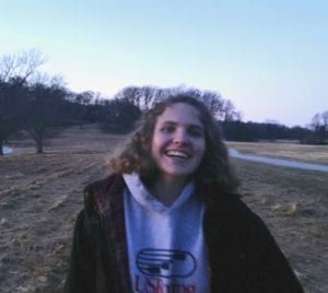 Partially blurry photo of a woman with blonde hair laughing in a outdoor scene