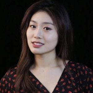 Headshot of the artist. She is wearing a black top with red flowers