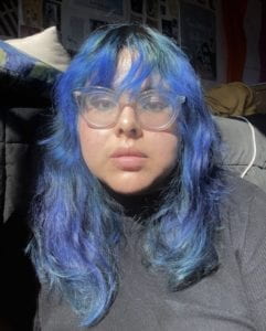 Woman with dyed blue hair and clear glasses