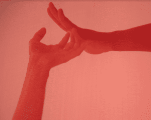 Red tinted photograph show two hands reaching towards and lightly touching each-other