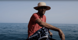 Man on a boat wearing a red shirt and straw hat