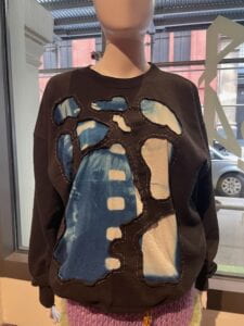 Photograph of a sweater made with photographs and textile patterns displayed on a mannequin. 