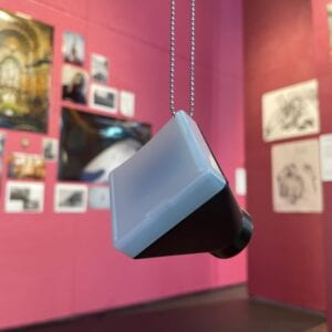 Photograph of a physical photo slide viewer hanging from a chain. 