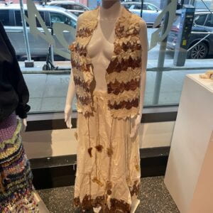 Two piece vest and skirt made from dried plants, cotton fabric, and algae bioplastic displayed on a mannequin.