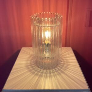 Photograph of an acrylic lamp that displays refracting shadows on a white pedestal. 