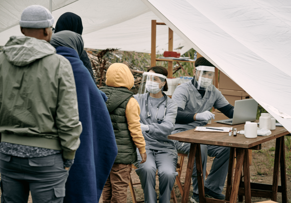 Health screeners checking individuals for sickness in a tent