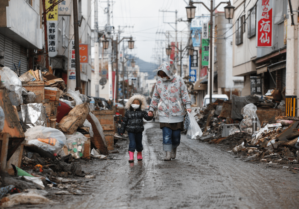 Woman and child walking in earthquake/tsunami wreckage.