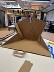 The chair-bag is made from brown cardboard. This photo shows unfolded to make a small "chair" that someone could sit in and lean on. 