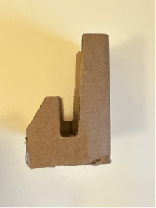 Side view of a "L" shaped phone stand made of cardboard.