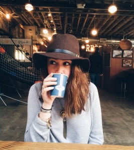 Author in wide brimmed brown hat drinking from a cup