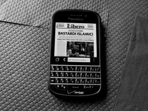 News article on phone screen reading "Bastardi Islamici"