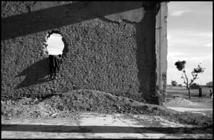 Little boy leaning into a large hole in a wall.