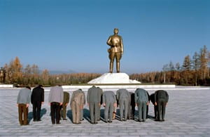 Group of people bowing at gold statue