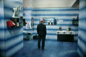 man in blue room standing in front of a mirror