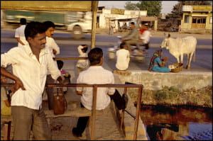 Men standing in town wearing dark pants and white shirts.