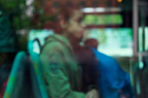 Woman sitting on bus viewed through blue tinted window