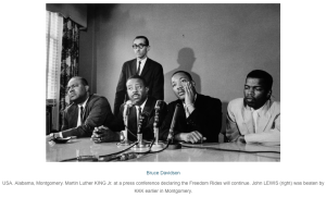 Dr. martin luther king jr. sitting at a table with microphones in front of him